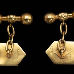 Back of gold shield shaped cufflinks. Chains to barbell togggles.