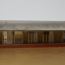 Model of a house with an arched roof, corrugated iron and wide expanses of glass.