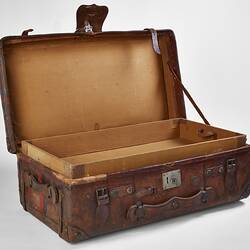 Worn brown leather suitcase with buckles. Lid open.