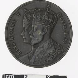 Round medal with profile of a crowned man and woman, text surrounding.