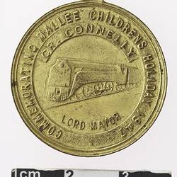 Round gold coloured medal with train, text surrounding.