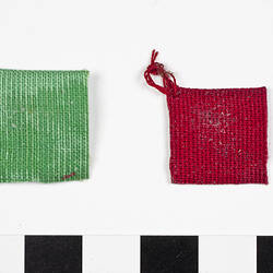 Two square cloth pot holders one red, one green.