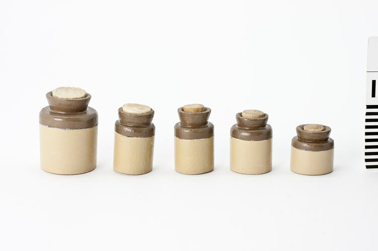 Five cream and brown canisters with stoppers.