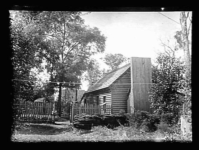 Wooden house with chimney and fenced yard.