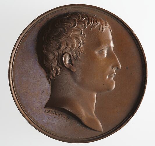 Round medal with profile of male facing right.