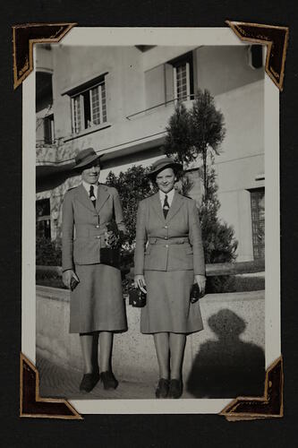 Two woman in uniform standing in front of building.