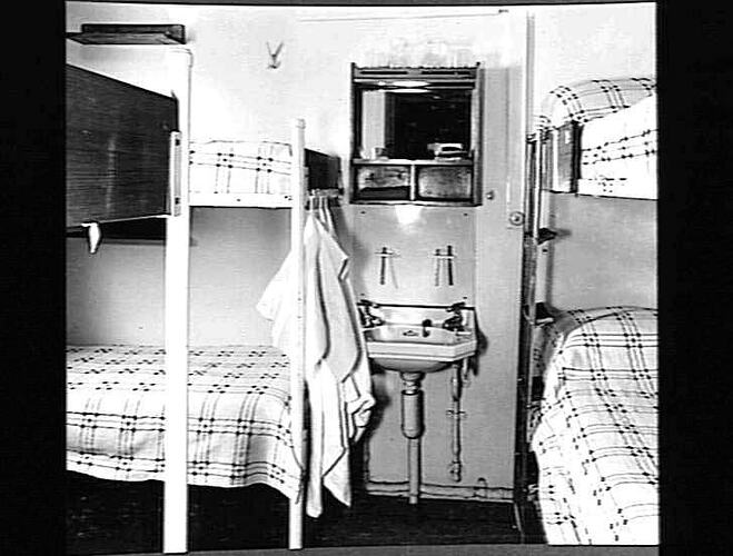Ship interior. Bunk beds on left and right. Handbasin in centre.