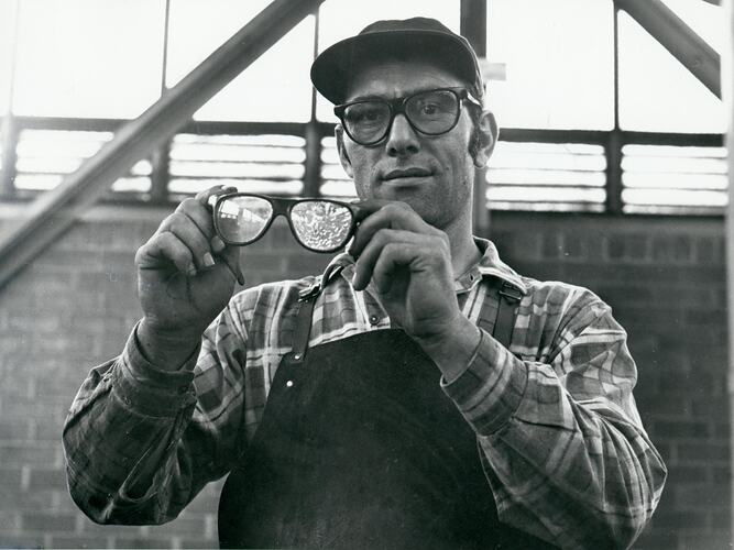 Man holding shattered safety glasses.
