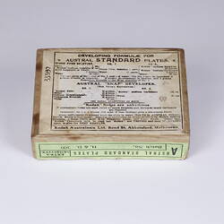 Underside of card box with black printing on the white label. Thin green label on side of box.