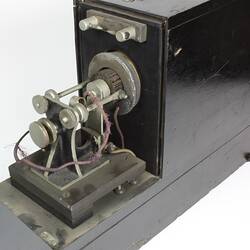 Grey box, open to show metal machine parts inside.