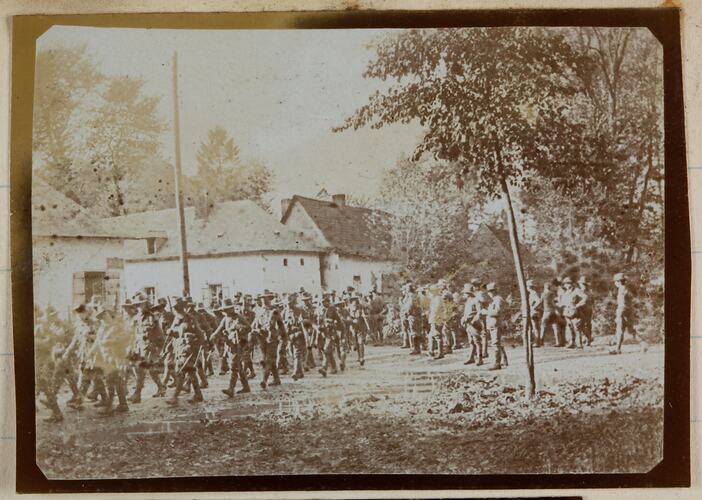 Soldiers marching in formation near buildings.