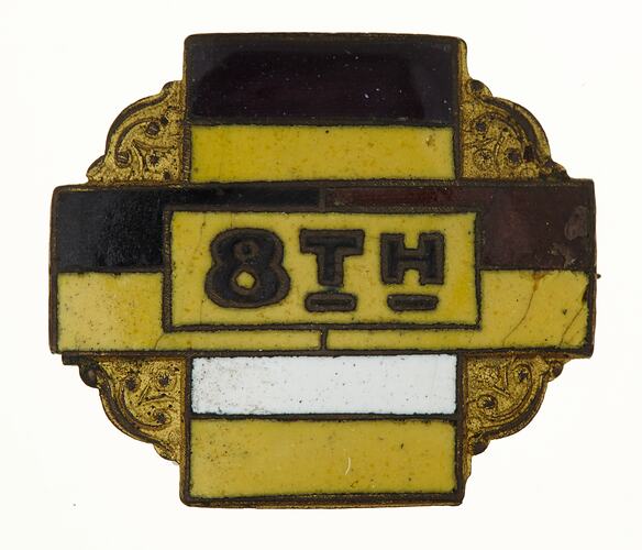 Enamel badge with yellow, black and white cross and black text.