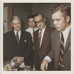 Four men looking down at scientific equipment.