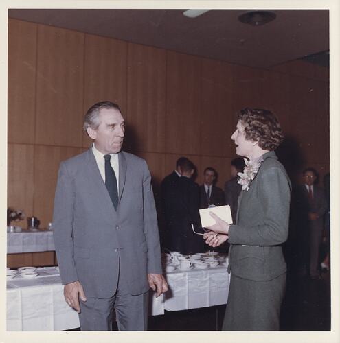 Woman in green speaking to man in suit.