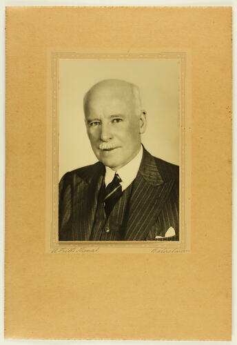 Head and shoulders portrait of balding man in dark suit.