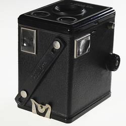 Black box-shaped camera, central lens, two circles at top. Three quarter view. Window on each side.