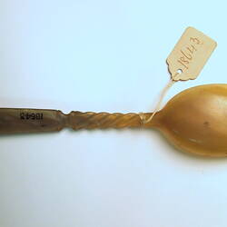 Horn spoon with paper label viewed from underside.