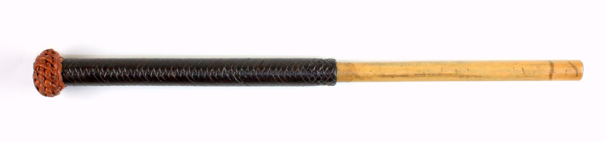 Wooden stick covered halfway along length with black braiding. Brown braided knob on end.