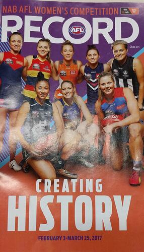 Front cover of glossy booklet with group portrait of female football team. White text.