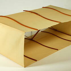 Box kite with two square sections made of cream fabric with wood and metal frame. Angle view.