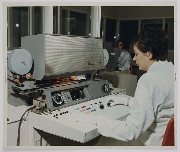 Woman seated at desk with a machine.