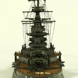 Naval ship with mast, front view.
