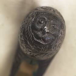 Ornate pistol handle tip with face of a lion.