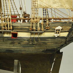 Wooden ship with three masts, rear side view.