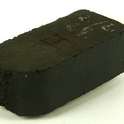 Rectangular black briquette with broken end.
