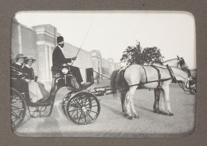 Nurses riding in carriage drawn by two horses.