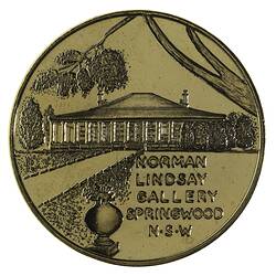 Round medal with house and trees.