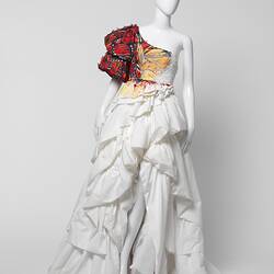 White ruffled wedding dress with oversized red butterfly-like shoulder detail on right side.