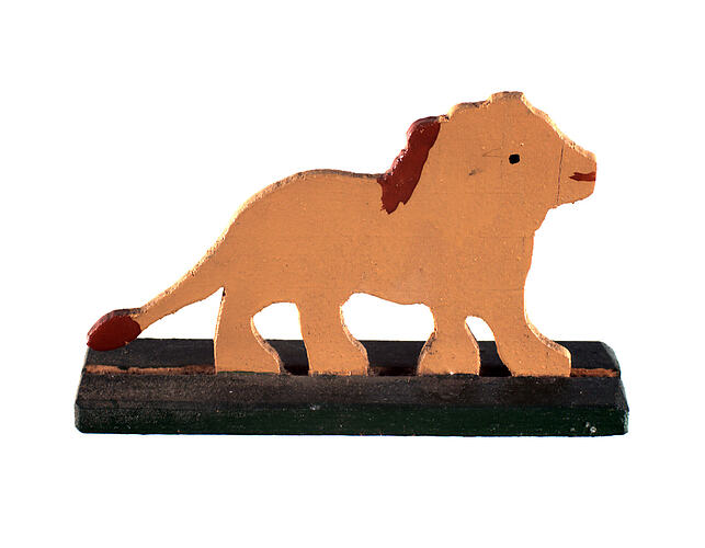 Side view of painted light brown wooden toy lion on black stand.