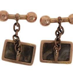 Back of rectangular rose gold cufflinks, each with a striped grey stone. Set in rose gold with chain attached to dumbbell-shaped toggle.