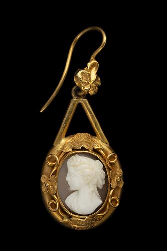 Gold mounted cameo earring. Round white cameo profile bust with brown background, gold border.