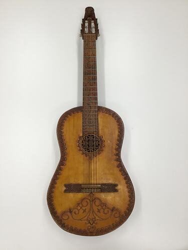 Brown wooden mandolin with carved decorations on body.