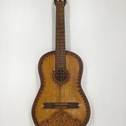 Brown wooden mandolin with carved decorations on body.