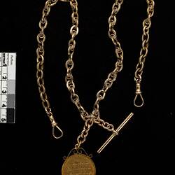Back of round fob with chain and T-bar.