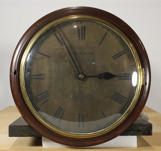 Round clock face with black numerals and wooden trim.
