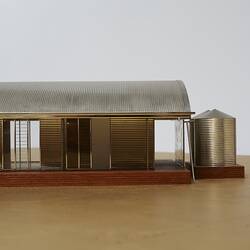 Model of a house with an arched roof, corrugated iron and wide expanses of glass.