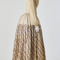Cream muslin dress, high neck, long sleeves, banded waist, full length gathered skirt. Bustle. Profile.