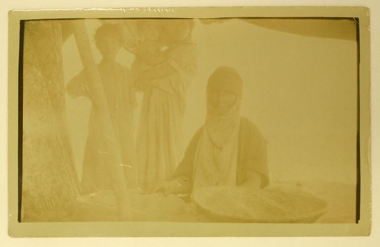 Seated woman with bowls of wheat.