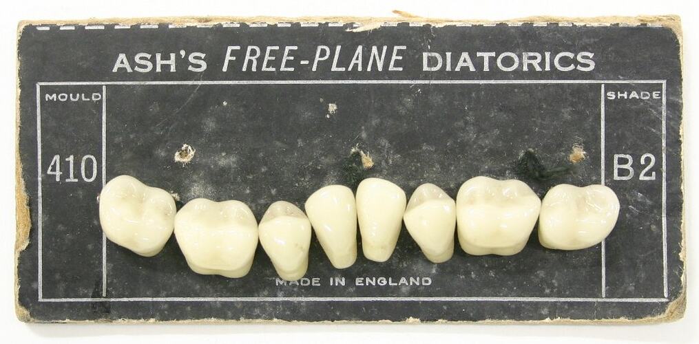 Eight artificial teeth on black cardboard