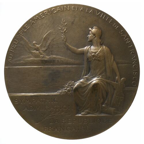 Medal with female seated on sea wall, holding up an olive branch to a bald eagle. Sun rays behind. Text around