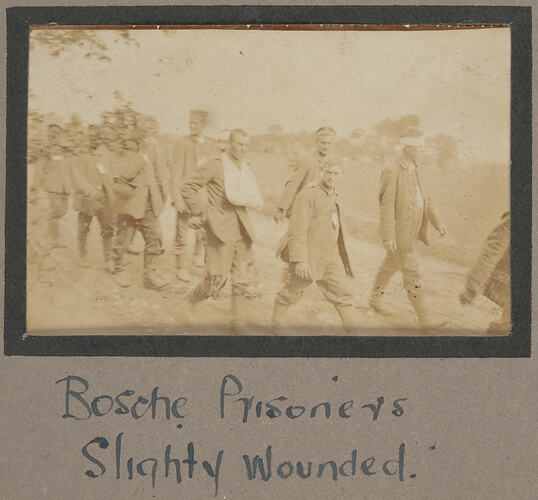 Group of soldiers walking down a road, two soldiers have bandaged injuries.