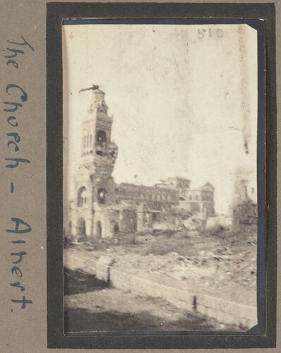 Partially destroyed stone building with attached bell tower still standing.