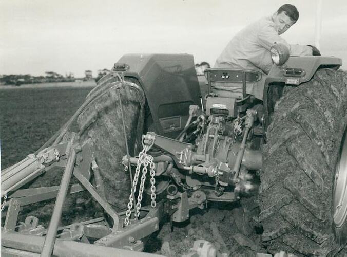 Man sitting on seat of a tractor looking behind him.