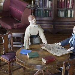 Woman and boy dolls in dolls house.