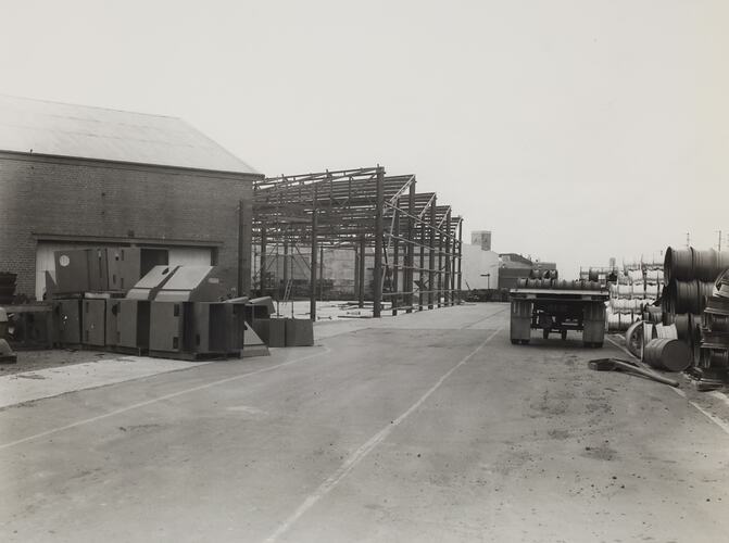 Road leading to factory exterior showing the construction of a sheet iron extension.
