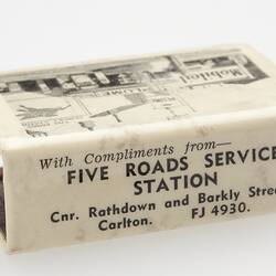 White matchbox cover with black printed image of service station.